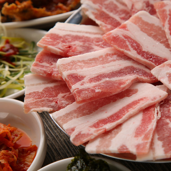 Raw sliced meat on a plate with side dishes in the background